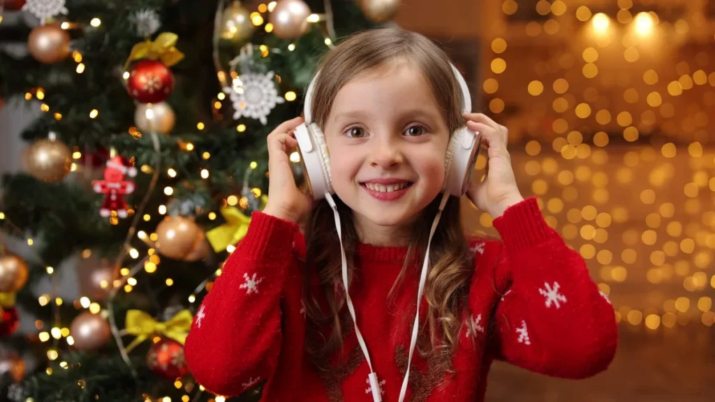 Imagem crianca ouvindo musica proximo a arvore de natal do artigo Músicas para ouvir e sentir o espírito do Natal