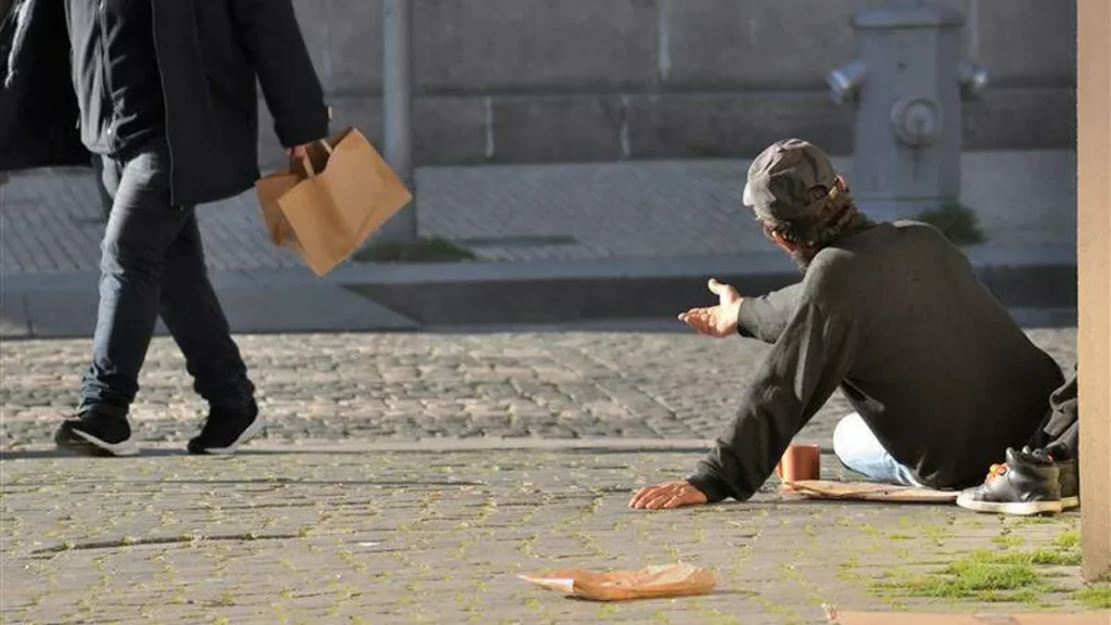 Imagem homem mendigo pedindo auxilio enquanto outro homem faz compras do artigo Natal e desigualdade social: o que a fé nos ensina a fazer