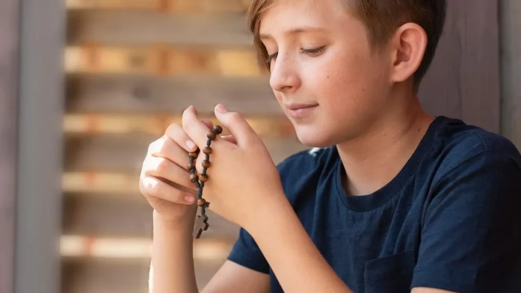 Imagem menino rezando o terco mariano do artigo Mistérios Gozosos: a alegria do Advento no Terço dos Homens