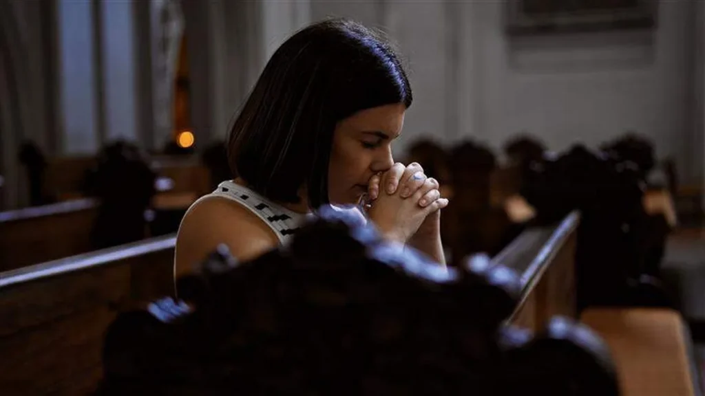 Imagem mulher orando na igreja do artigo Rezar pelo outro: o elo cristão que nenhuma tecnologia substitui
