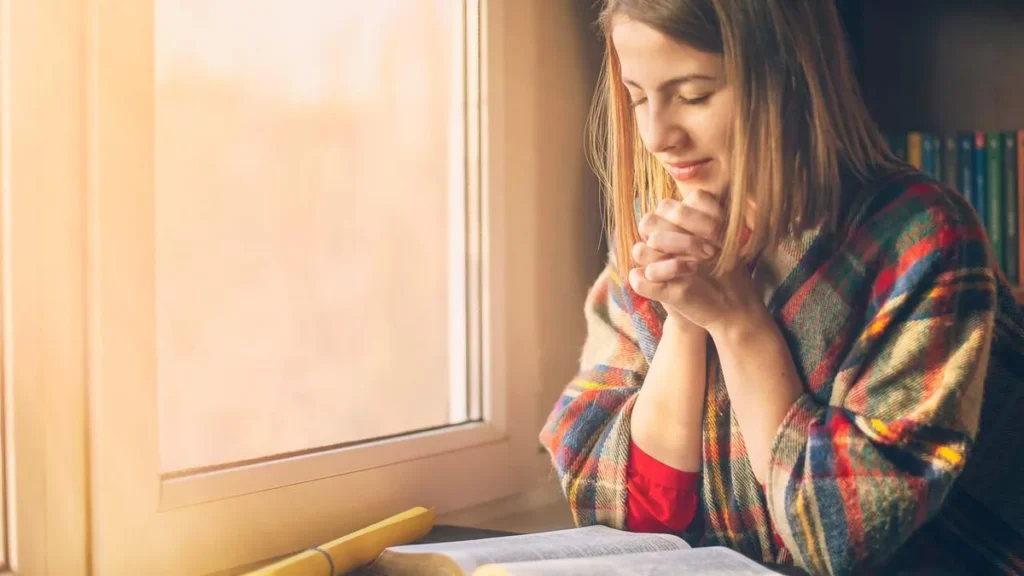 Imagem mulher rezando com biblia do artigo Dica de leitura: 70 orações para encorajar o viver