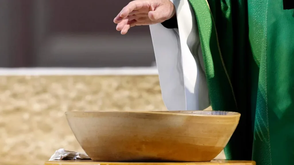 Imagem padre abencoando a pia batismal do artigo Batismo de adultos: o que a Igreja ensina e como funciona?