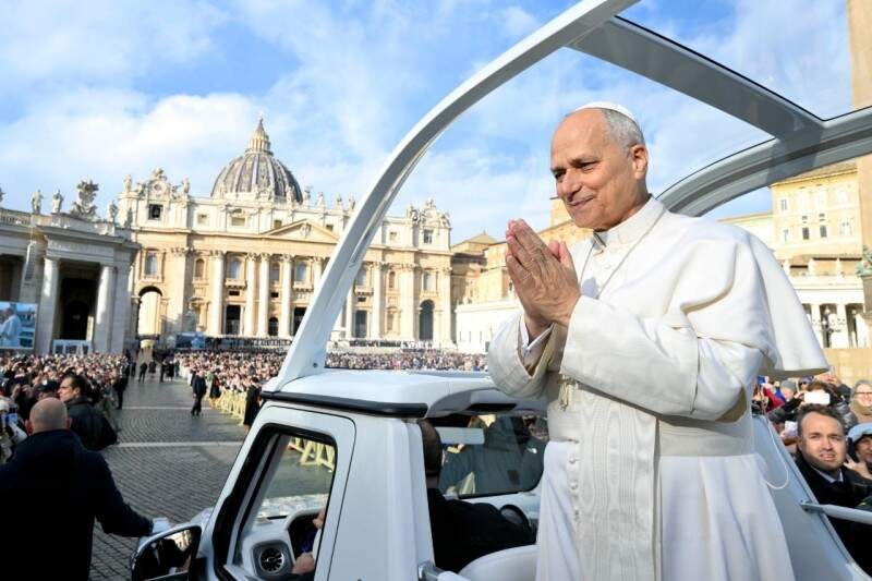 Papa Leao xiv no papamovel com as mãos postas sorrindo cumprimentando fieis na praça são pedro em 2025 (Vatican Media)