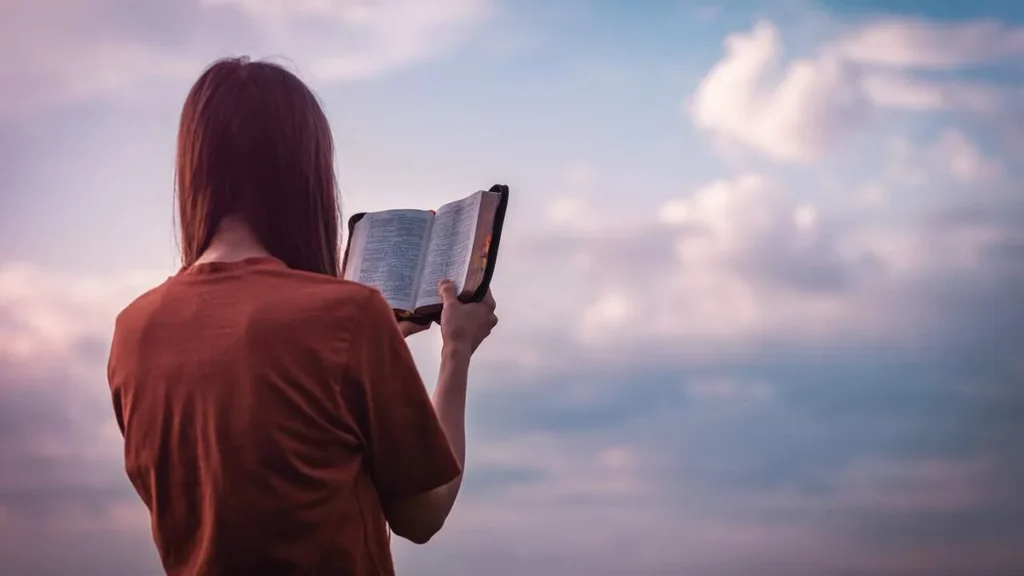 Imagem mulher segurando a biblia de frente para o ceu do artigo Retiro Quaresmal: meditações para cada dia até a Páscoa