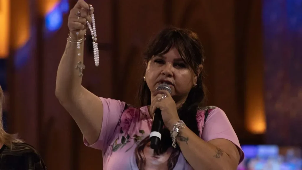 Imagem mulher ergue o terco enquanto reza o terco na romaria do terco das mulheres no altar central em 2025 do artigo O papel da mulher devota no grupo de Terço das Mulheres