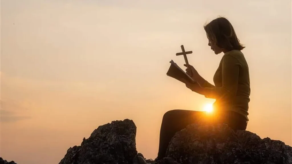 Imagem mulher rezando por do sol ao fundo do artigo Reflexão Semanal: Ser sal e luz é a missão de todo cristão