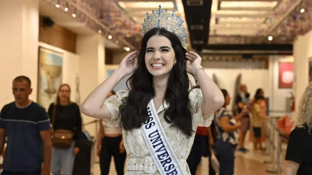 Imagem miss brasil maria gabriela lacerda com as maos proximas a coroa em frente a sala das promessas do artigo Miss Brasil homenageia a Mãe Aparecida com entrega de ex-voto