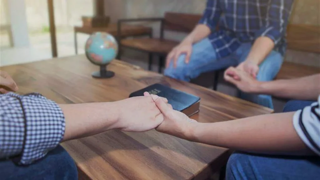Imagem Pessoas de maos dadas em circulo sob a mesa um globo e uma biblia do artigo Todo cristão é um missionário?