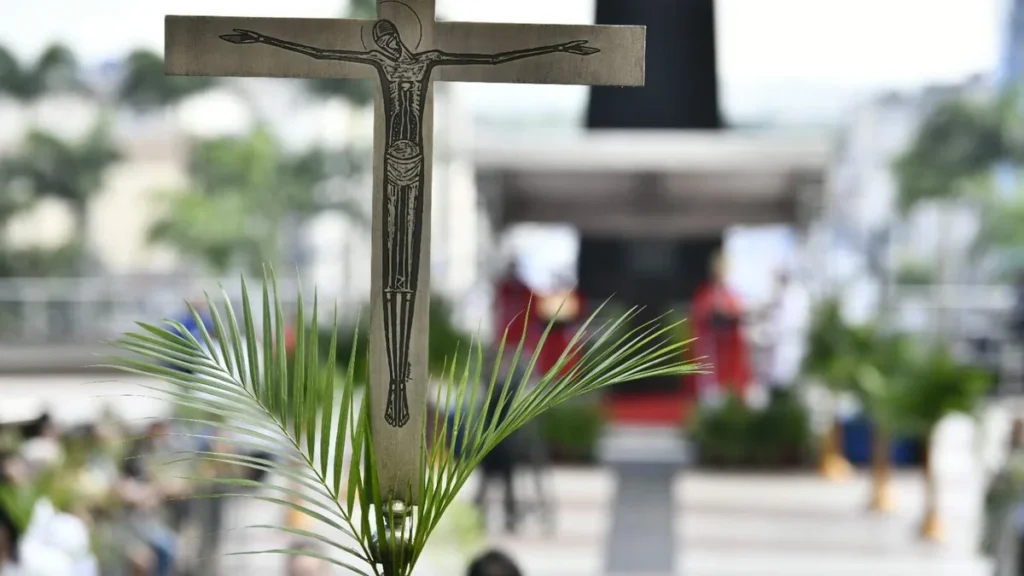 Imagem cruz do baculo com os ramos inseridos em momento da procissao de semana santa 2026 do artigo Missa de Domingo de Ramos destaca a inocência de Jesus