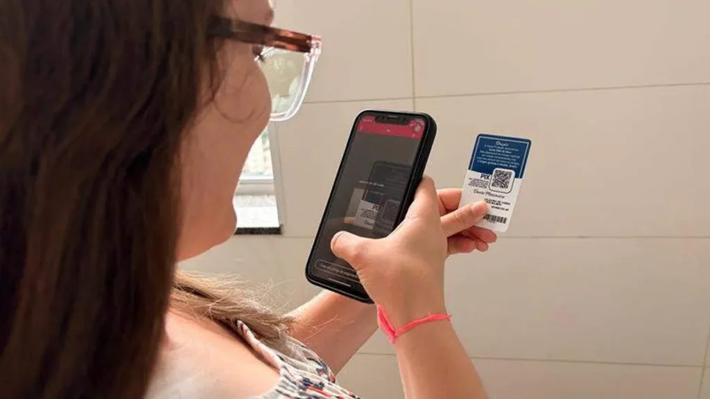 Imagem Mulher com celular e cartao do devoto na mao do artigo Faça a sua doação pelo Cartão do Devoto: é rápido e fácil!
