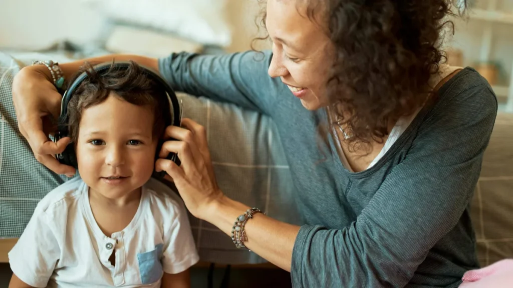 Imagem mae e filho compartilhando um fone de ouvido para ouvir musica do artigo “Sou de Fé” destaca o amor materno como reflexo do amor de Deus