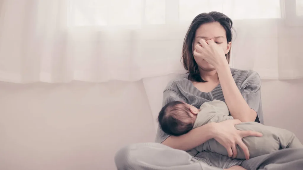 Imagem mae cansada com bebe no colo do artigo “Diálogos da Mente” propõe olhar mais gentil para a maternidade