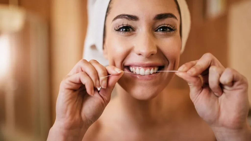 Imagem Mulher usando fio dental nos dentes do artigo Vida Saudável traz um olhar sobre a saúde bucal