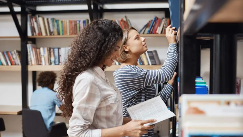 Imagem Duas estudantes em uma biblioteca do artigo Sou de Fé fala sobre a pressão das escolhas no vestibular