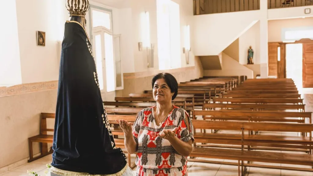 Imagem senhora rezando de frente para nossa senhora aparecida em uma igreja do artigo Salve Rainha: mostrai-nos Jesus, bendito fruto do teu ventre