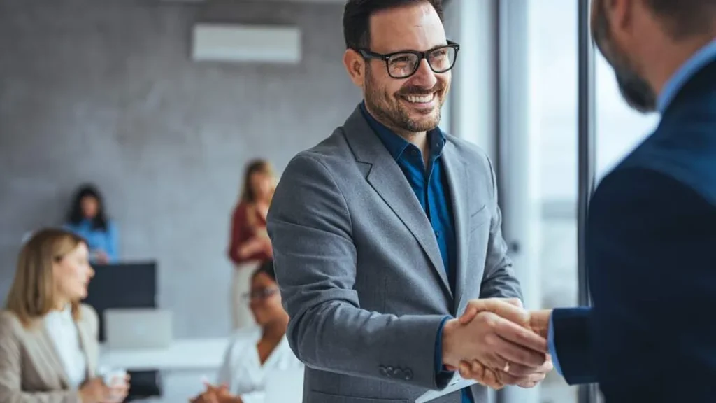 Imagem Homens se cumprimentando no trabalho do artigo Dia do Trabalhador: como está sua confiança no seu ambiente de trabalho?