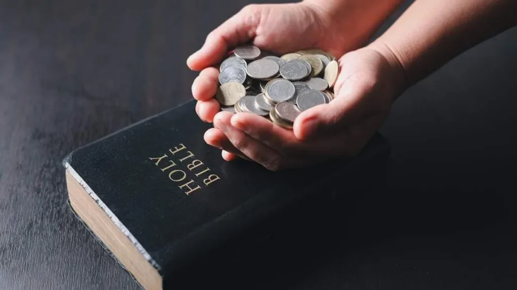Imagem Maos dando dizimo proximo a Biblia do artigo Os católicos estão obrigados a dar o dízimo?